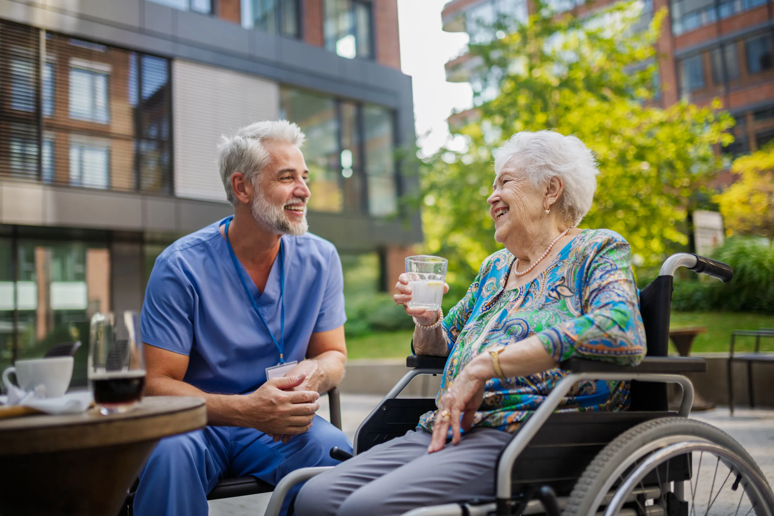 Male nurse having cup of coffee with senior patient in a wheelchair Male nurse having cup of coffee with senior patient in a wheelchair